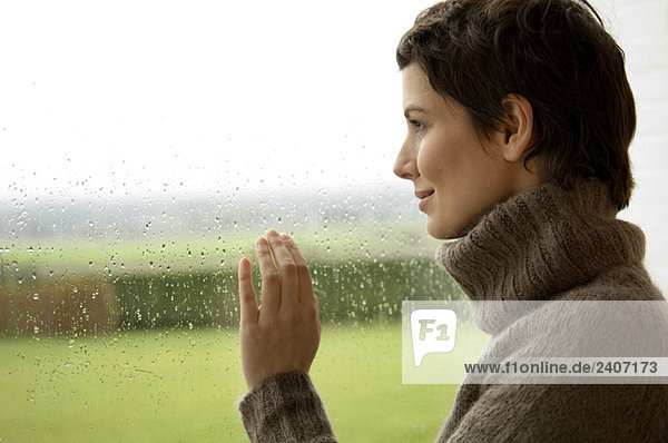 Mittlere erwachsene Frau mit Blick aus dem Fenster