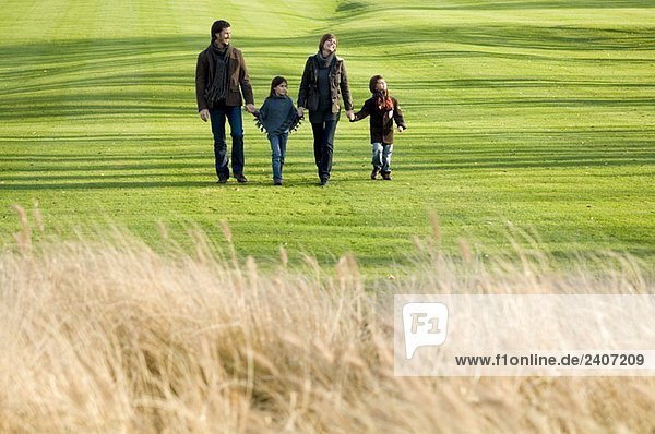 Two children with their parents walking in a park