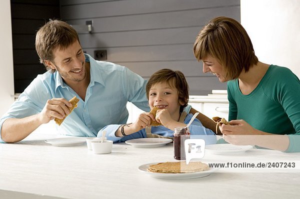 Ein erwachsener Mann und eine junge Frau beim Frühstück mit ihrem Sohn.