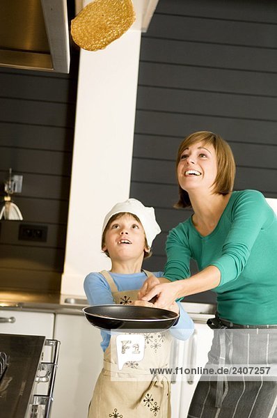 Young woman flipping a pancake with her son