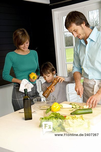 Ein erwachsener Mann und eine junge Frau  die mit ihrem Sohn in der Küche Essen zubereiten.