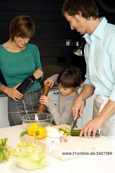 Mid adult man and a young woman preparing food with their son