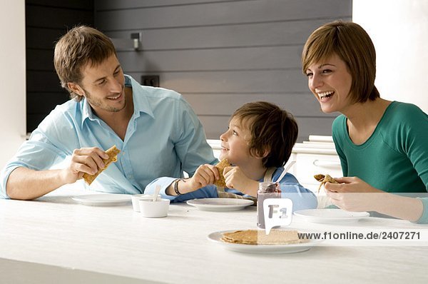 Mid adult man and a young woman having breakfast with their son
