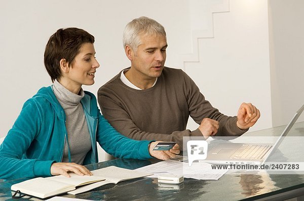 Mature man and a mid adult woman working on a laptop and holding a credit card