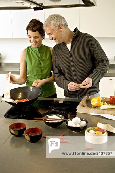 Mature man and a mid adult woman preparing food in the kitchen