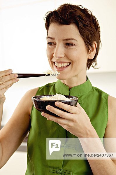 Nahaufnahme einer erwachsenen Frau  die Reis mit Essstäbchen isst.