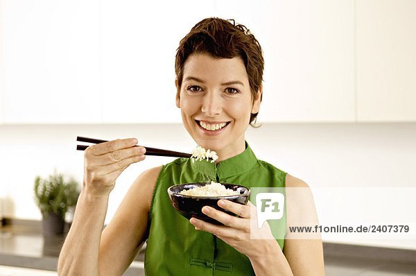 Porträt einer erwachsenen Frau beim Essen von Reis mit Stäbchen