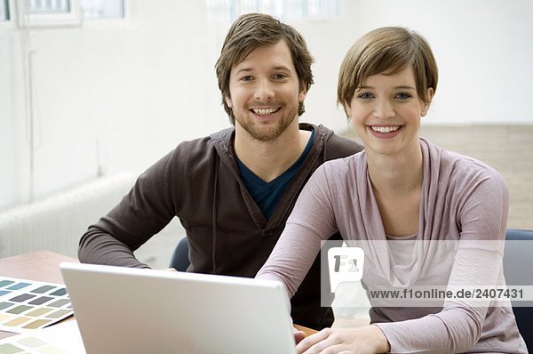 Portrait of a mid adult man and a young woman using a laptop