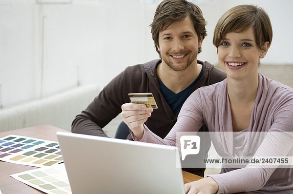 Mid adult man and a young woman using a laptop and holding a credit card
