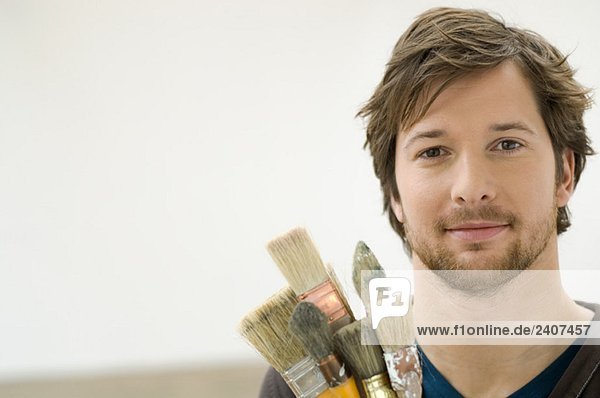 Portrait of a mid adult man holding paintbrushes