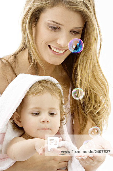 Nahaufnahme einer jungen Frau und ihres Sohnes beim Spielen mit Seifenblasen