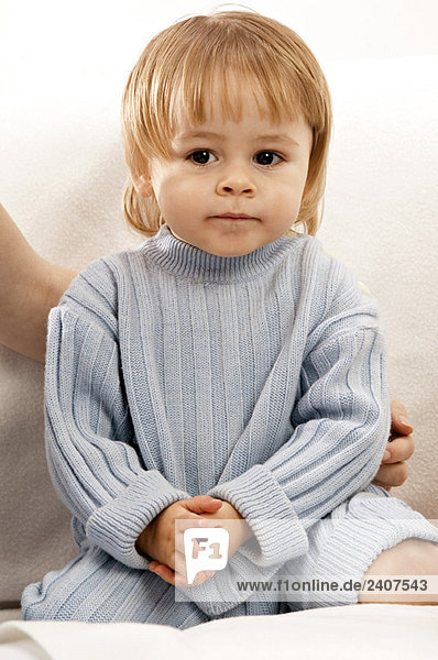 Nahaufnahme eines kleinen Jungen  der auf einer Couch sitzt und lächelt.