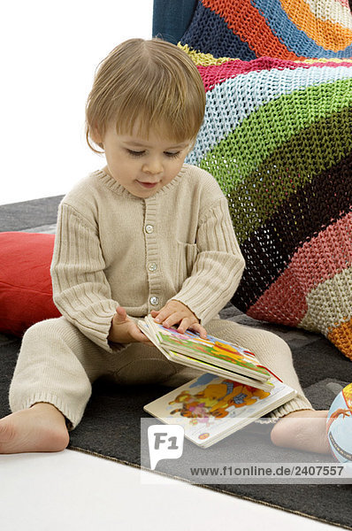 Nahaufnahme eines kleinen Jungen  der Bilderbücher hält und sitzt