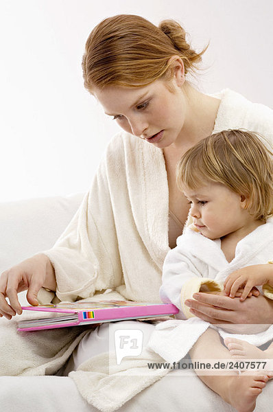 Nahaufnahme einer jungen Frau  die mit ihrem kleinen Jungen sitzt und sich ein Bilderbuch ansieht.