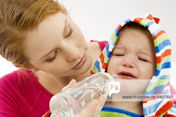 Nahaufnahme einer jungen Frau  die sich von einer Babyflasche an ihren weinenden Sohn ernährt.