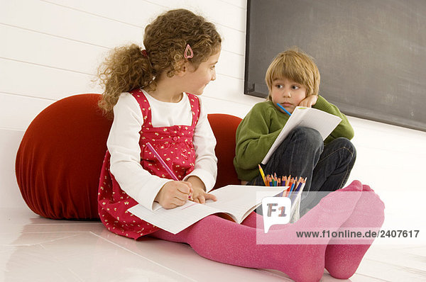 Junge und Mädchen zeichnen auf Notizblöcken