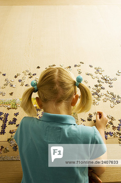 Rückansicht eines Mädchens beim Puzzlespielen