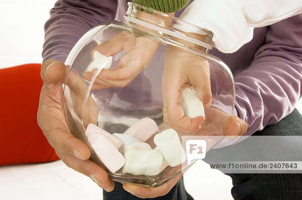 Kinder holen Marshmallows aus einem Glasbehälter seines Vaters.