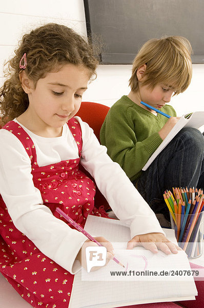 Zwei Kinder zeichnen auf einem Notizblock