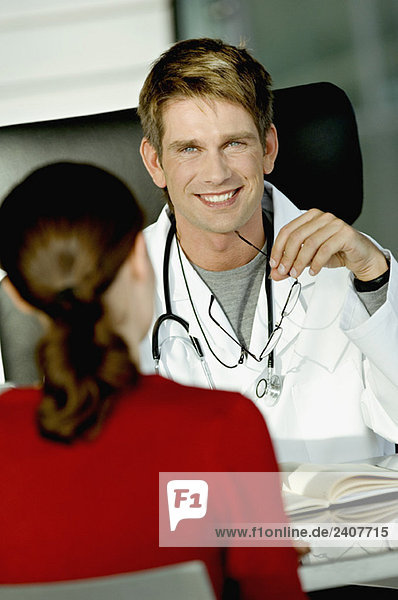 Porträt eines Arztes im Gespräch mit einer Patientin in seiner Praxis