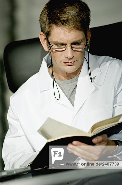 Close-up of a male doctor sitting at a desk and reading a notebook