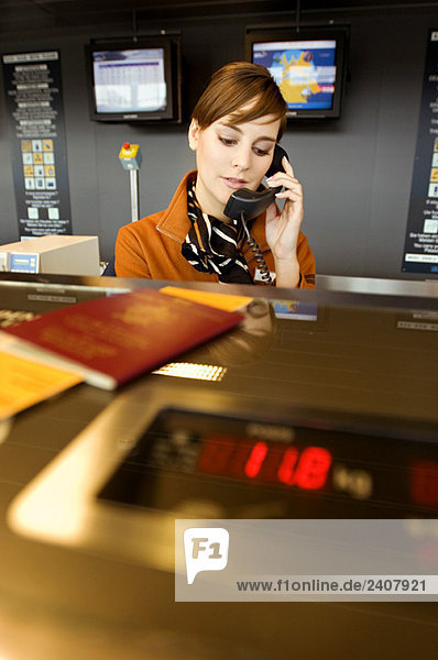 Female airline check-in attendant talking on the telephone