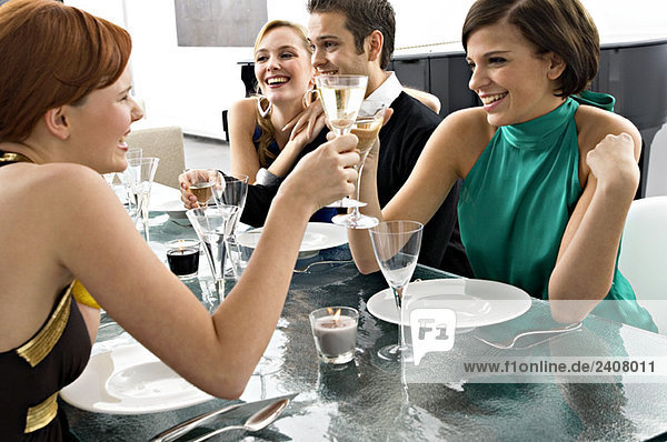 Zwei junge Frauen stoßen mit Champagner auf einer Dinnerparty an.