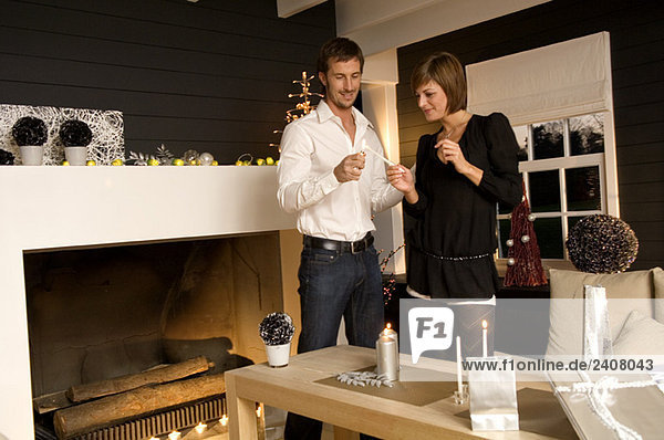 Ein erwachsener Mann und eine junge Frau  die eine Kerze mit einem Zigarettenanzünder anzünden.