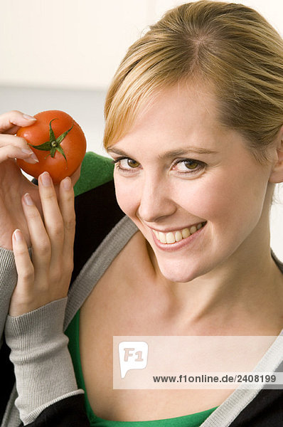 Porträt einer jungen Frau mit einer Tomate