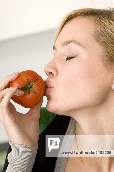 Nahaufnahme einer jungen Frau beim Küssen einer Tomate