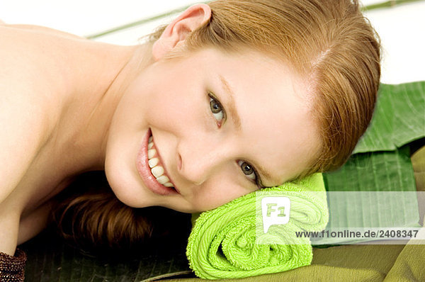 Porträt einer jungen Frau auf einem Massagetisch liegend und lächelnd
