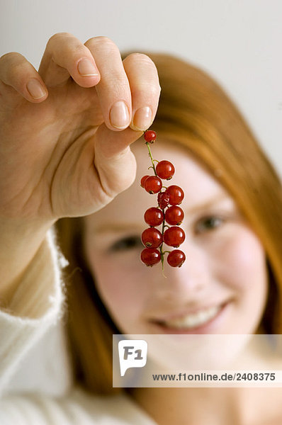 Close-up of a young woman holding a bunch of red currants