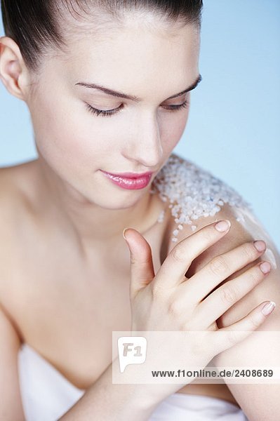 Young woman rubbing her shoulder with salt