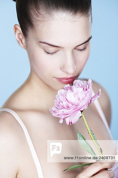Young woman smelling peony