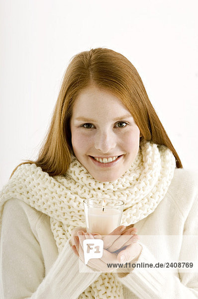 Porträt einer jungen Frau  die eine brennende Kerze hält und lächelt