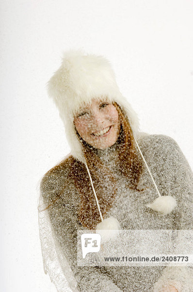 Porträt einer jungen Frau im Schnee stehend und lächelnd
