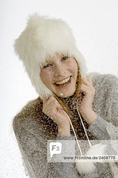 Porträt einer jungen Frau  die beim Schneefall lächelt
