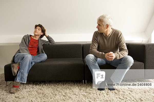 Mature man and his son sitting on a couch