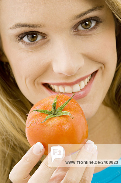 Porträt einer jungen Frau mit Tomate und Lächeln