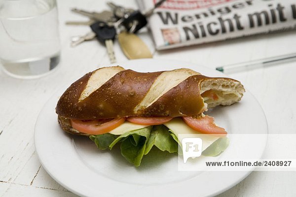 Ein U-Boot-Sandwich mit Tomaten  Salat und Käse auf einem Teller mit einem Biss davon.