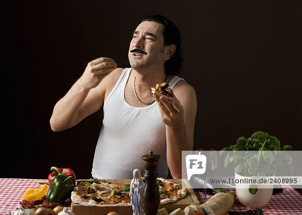 Stereotypischer Italiener  der Pizza isst und mit der Hand gestikuliert.