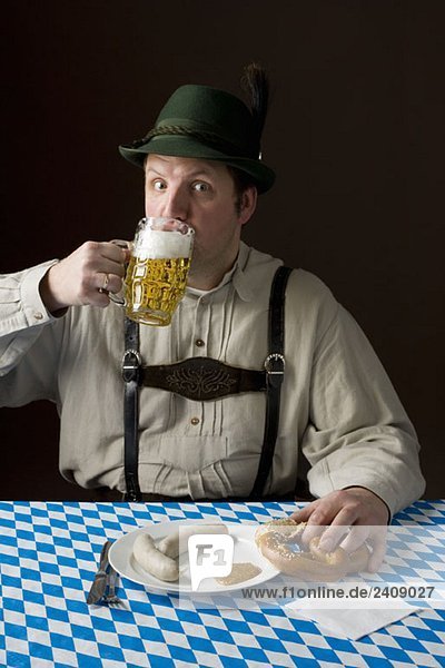 Stereotypischer deutscher Mann in bayerischer Tracht bei Bier und deutschem Essen