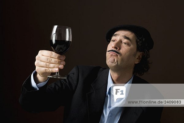 Ein stereotyper Franzose  der auf ein Glas Rotwein starrt.