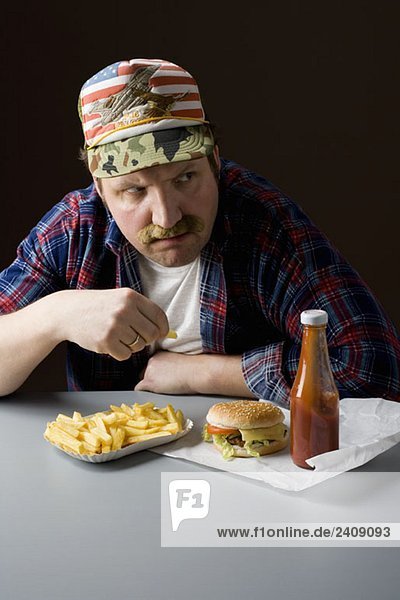 Stereotypischer amerikanischer Mann  der eine Fastfood-Mahlzeit isst.