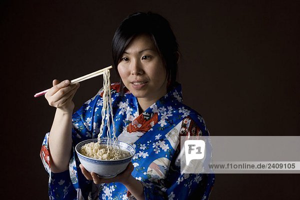 Eine Frau im Kimono  die Nudeln isst.