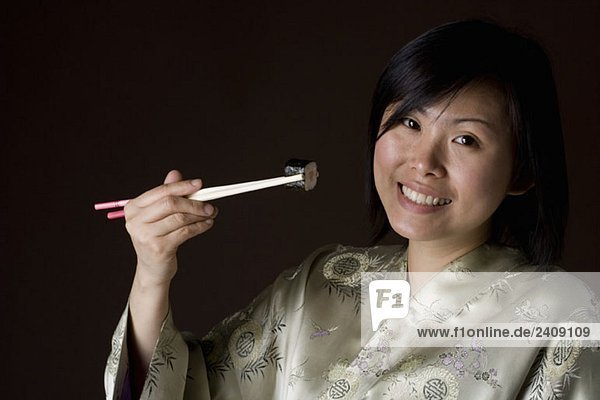 Eine Frau in einem Kimono  die Sushi isst.