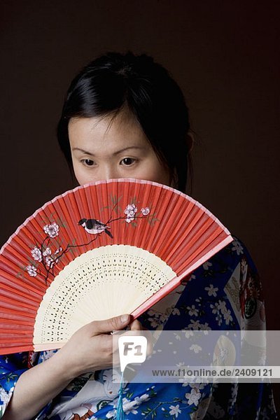 Eine Frau in einem Kimono mit einem Faltfächer