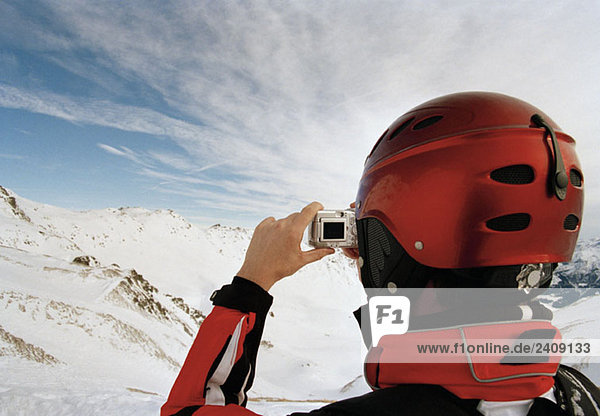 Ein Skifahrer beim Fotografieren der österreichischen Alpen