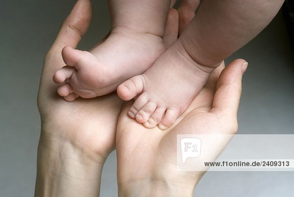 Close up of mother holding newborn’s feet