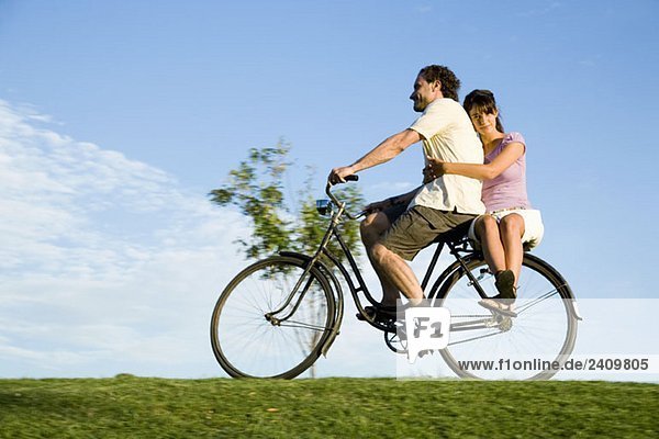 A man riding a bicycle and a young woman sitting on the back